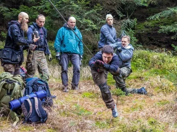 Mann zieht sich an einer selbstgebauten Seilbrücke mit einem Seil hoch
