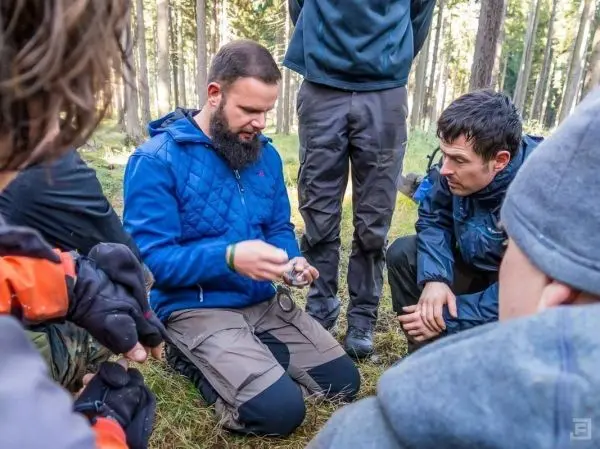 Person erklärt die Benutzung eines Kompasses an Gruppe im Wald beim Überlebenstraining
