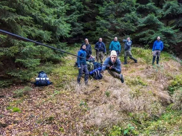 Person schwingt an selbstgebauter Seilbrücke, Gruppe beobachtet