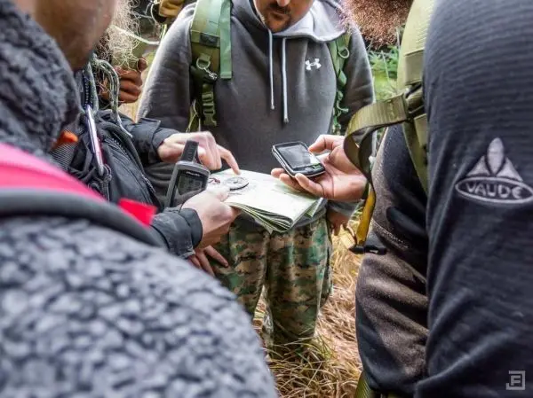 Personen betrachten Karten und Geräte im Freien beim Überlebenstraining