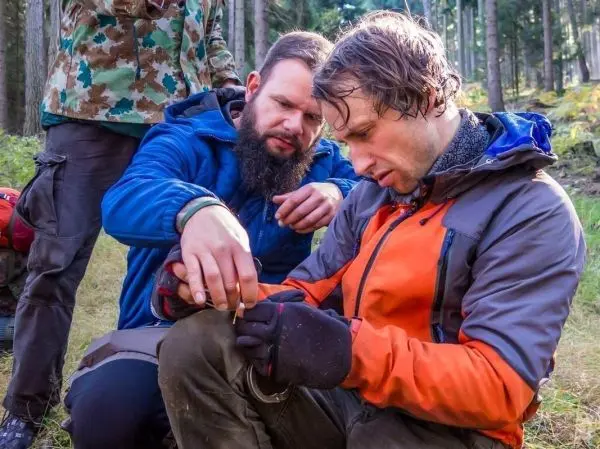 Zwei Personen arbeiten gemeinsam an einem Zunder, während eine dritte Person zuschaut