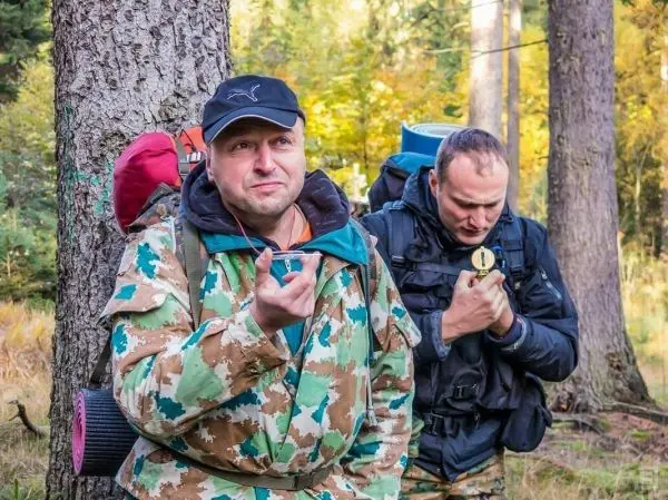 Zwei Personen mit Rucksäcken stehen im Wald und betrachten eine Kompassnadel