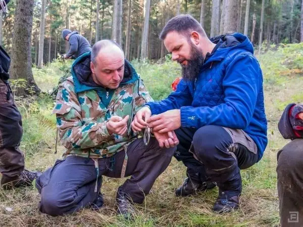 Zwei Personen prüfen Ausrüstung im Wald beim Survival Training