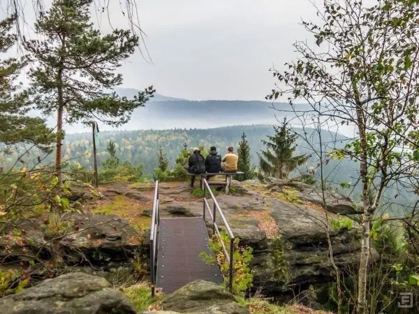 Zwei Personen sitzen auf einer Bank und blicken in die Landschaft