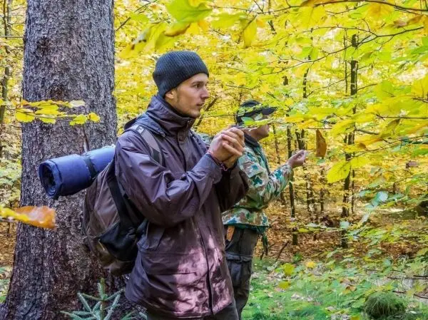 Zwei Personen stehen im Wald und betrachten die Umgebung zwischen bunten Blättern