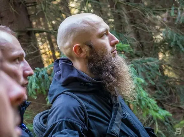 Zwei Personen stehen im Wald und schauen in verschiedene Richtungen