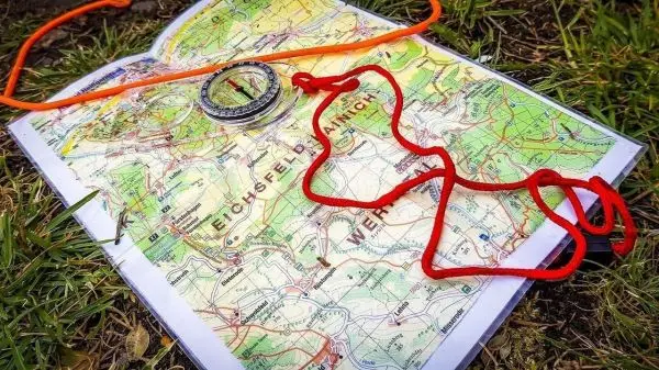 Karte mit Kompass und roten Schnüren auf grünem Untergrund