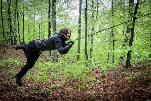 Person schwingt an einem Seil durch den Wald