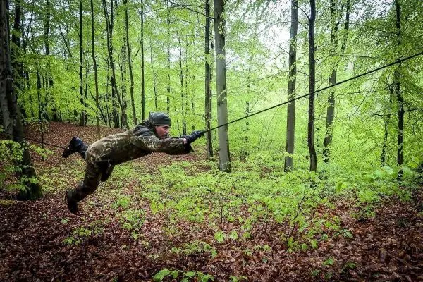 Person schwingt an einem Seil durch den Wald beim Survival Training