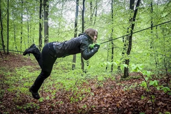 Person schwingt an einem Seil zwischen Bäumen