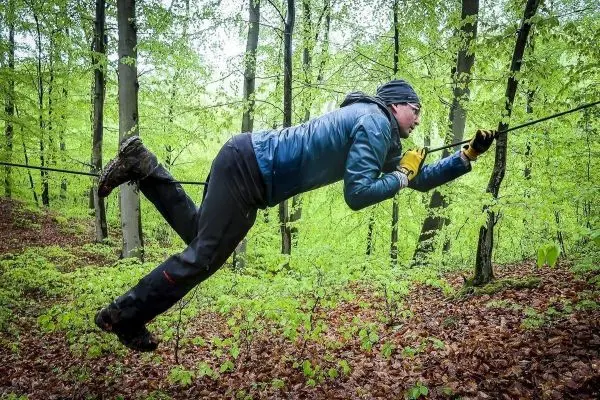 Person schwingt an einem Seil zwischen Bäumen