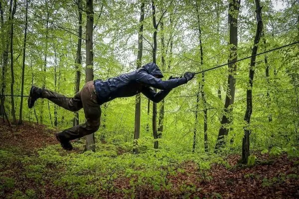Person schwingt an einem Seil zwischen Bäumen