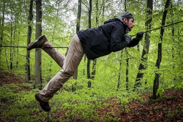 Person schwingt sich an einem Seil durch den Wald beim Survival Training