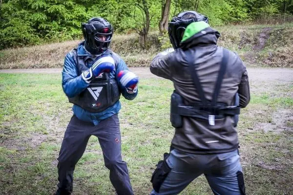 Zwei Kämpfer in Schutzausrüstung führen ein Sparring im Freien durch