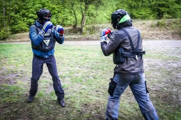 Zwei Kämpfer in Schutzausrüstung stehen sich gegenüber und bereiten sich auf einen Boxkampf vor