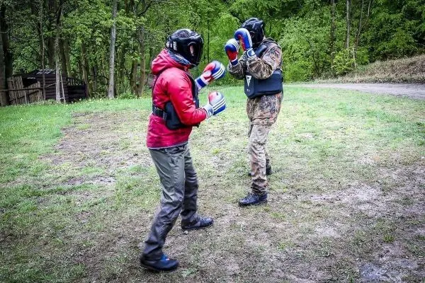 Zwei Personen im Boxkampf tragen Schutzausrüstung und Boxhandschuhe auf einer Wiese
