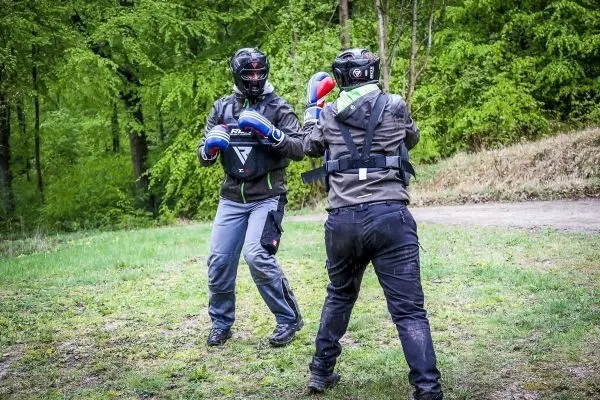 Zwei Personen in Schutzausrüstung üben Boxtechniken im Freien