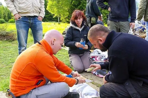 Drei Personen sitzen im Freien und bereiten Materialien auf dem Boden vor