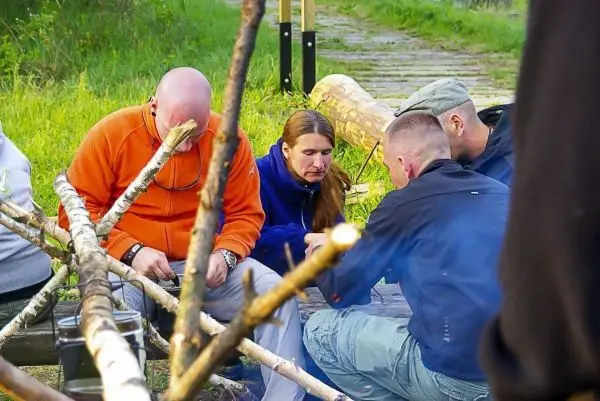Gruppe arbeitet gemeinsam an einem Feuerplatz mit Holz und Ausrüstung