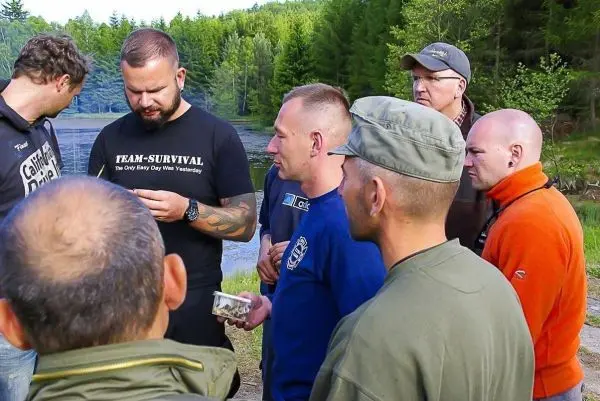Gruppe betrachtet Materialien am Ufer eines Gewässers in der Natur