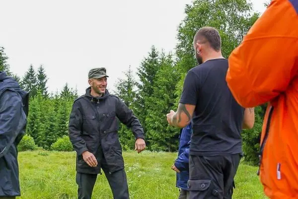 Gruppe diskutiert im Freien, umgeben von Bäumen und Wiese