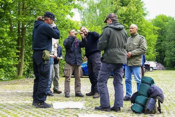 Gruppe diskutiert um einen Tisch mit Karten und Ausrüstung im Freien