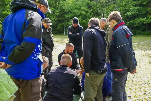 Gruppe um einen Tisch versammelt, diskutiert über Karten und Orientierungstechniken