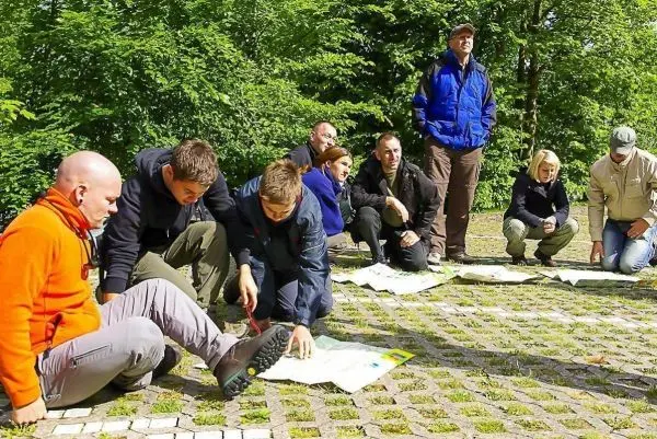 Gruppenteilnehmer analysieren Karten auf dem Boden in einer Waldumgebung