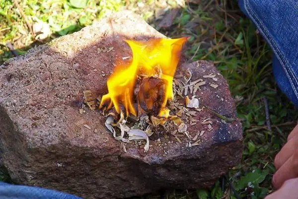 Kleine Flamme brennt auf Zunder, der auf einem Stein liegt
