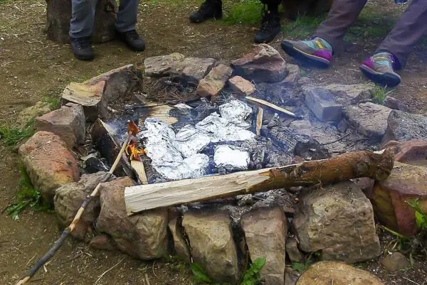 Kleine Flamme in einem Steinkreis mit Alufolie und Holzstücken