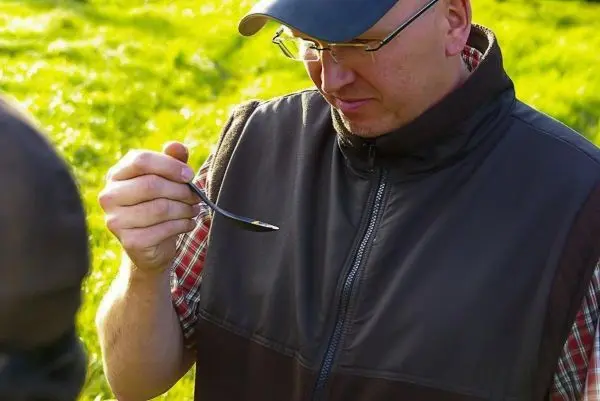 Mann hält einen Löffel und betrachtet dessen Inhalt aufmerksam