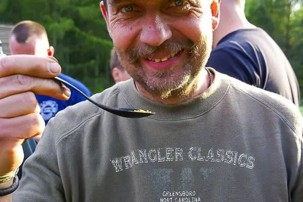 Mann hält Löffel mit Nahrung in der Hand und lächelt