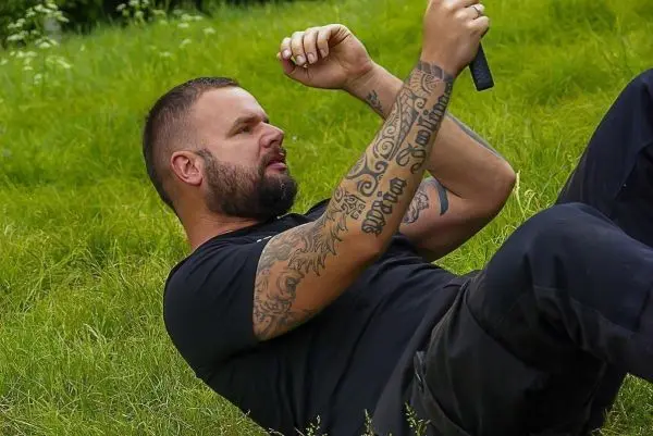 Mann liegt auf dem Rücken im Gras und hält ein Messer in der Hand