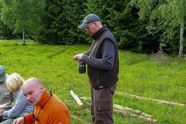 Mann steht in der Natur und hält einen Behälter in der Hand