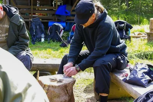 Messer bearbeitet Holzstück auf einem Baumstumpf im Freien