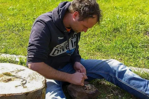 Messer schnitzt Zunder aus einem Holzstück auf einem Baumstumpf