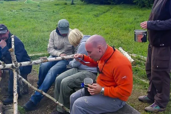 Person arbeitet mit einem Messer an einem Holzstück in einer Gruppe