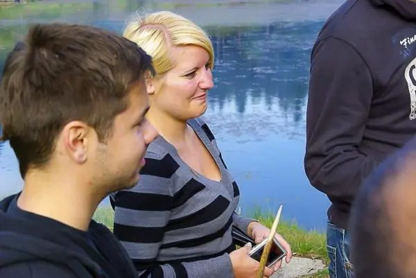 Person hält Notizbuch und schaut auf Wasseroberfläche