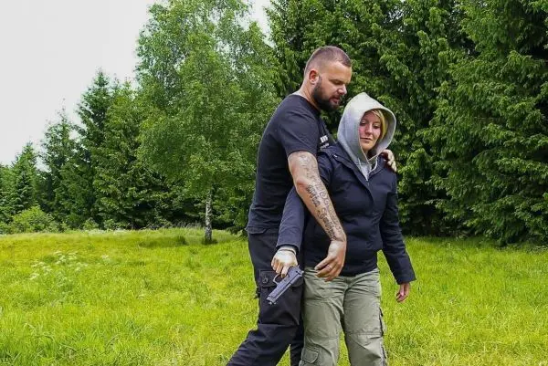 Person zeigt einer anderen Person den Umgang mit einer Waffe