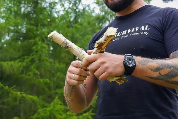 Zwei Holzstücke werden in der Hand gehalten und bearbeitet