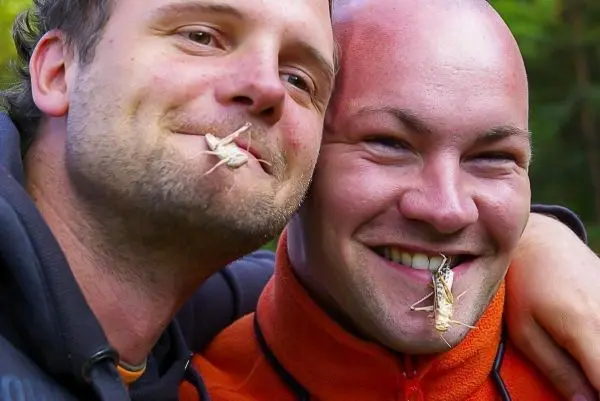 Zwei Männer lächeln mit Insekten im Mund