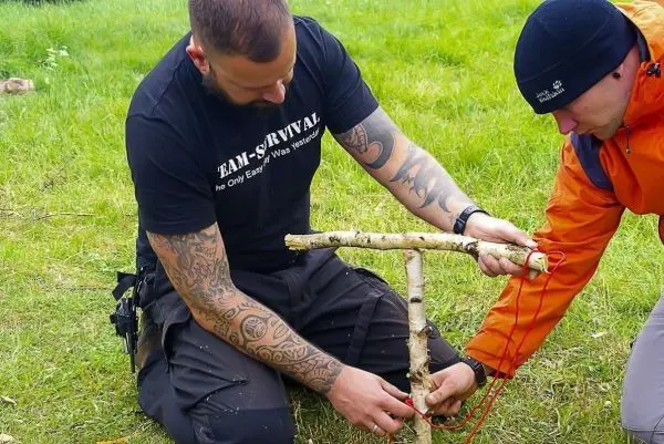 Zwei Personen bauen eine selbstgebaute Konstruktion mit Holzstücken und Schnur