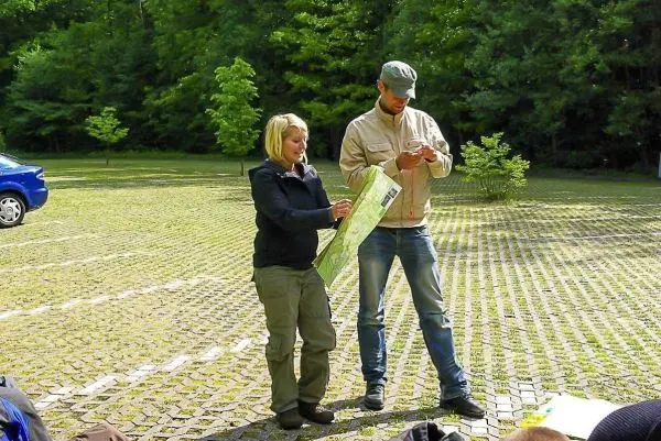 Zwei Personen betrachten eine Karte, während eine Person ein Smartphone nutzt