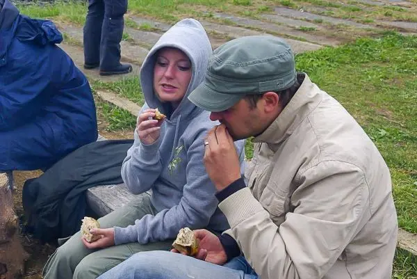 Zwei Personen sitzen auf einer Holzbank und essen Brot