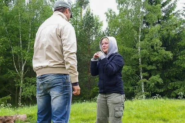 Zwei Personen stehen in einer grünen Wiese und scheinen zu kommunizieren
