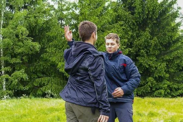 Zwei Personen stehen sich gegenüber und führen eine Übung im Freien durch