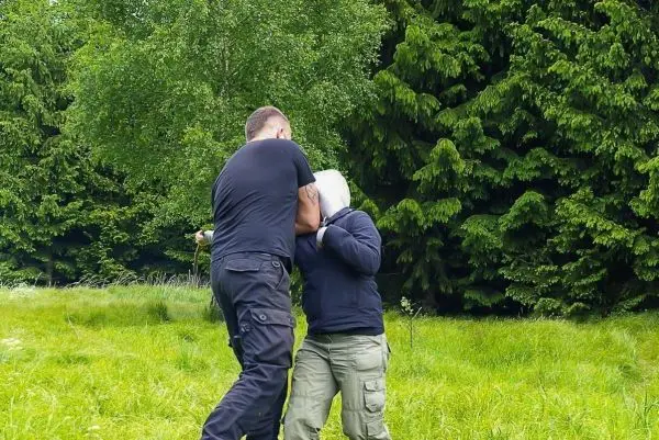 Zwei Personen üben eine Selbstverteidigungstechnik in einer grünen Wiese