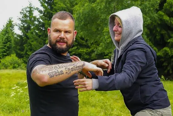 Zwei Personen üben eine Selbstverteidigungstechnik in einer grünen Wiese