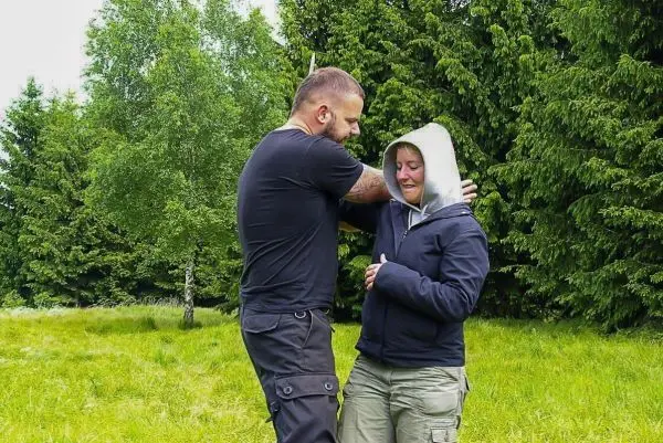 Zwei Personen üben eine Selbstverteidigungstechnik in einer grünen Wiese