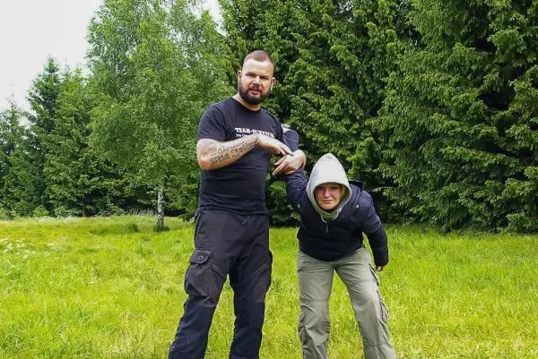 Zwei Personen üben eine Technik zur Kontrolle in einer Wiese mit Bäumen